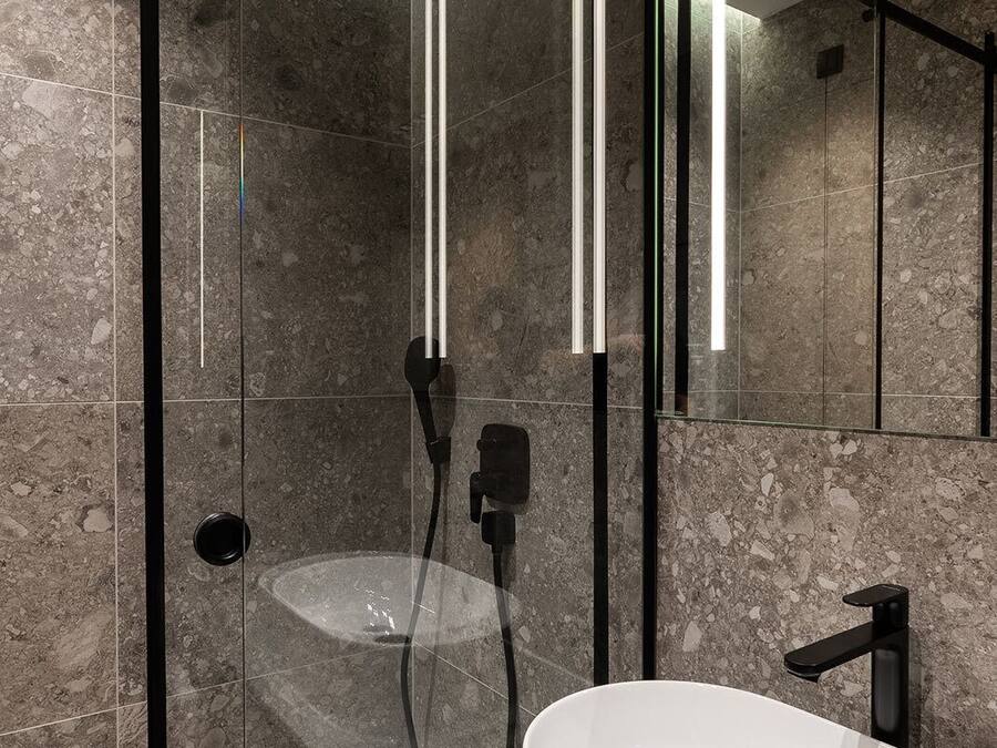 Een moderne badkamer met een douche met glazen wand, een wit wastafelmeubel en een grote spiegel.