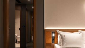 Ein modernes Hotelzimmer mit einem Holzkopfende, einem Nachttisch und einem großen Bett mit weißer Bettwäsche.