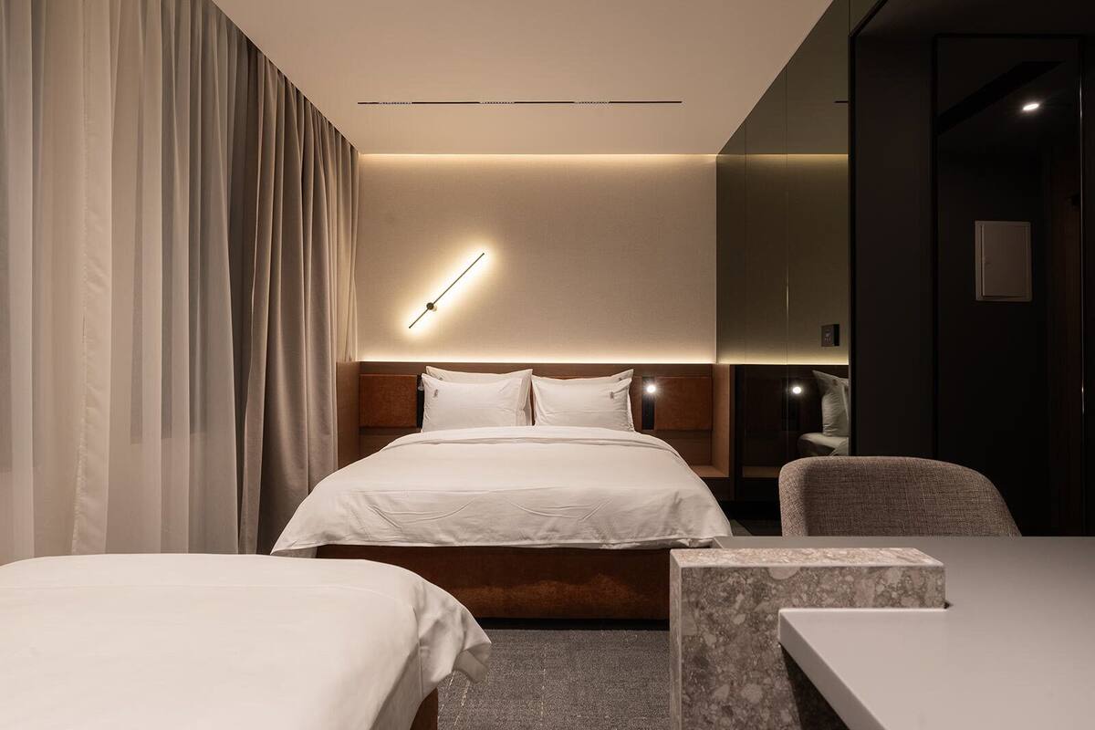 Une chambre d’hôtel moderne équipée d’un grand lit, d’un lit plus petit, d’un bureau et d’une chaise.