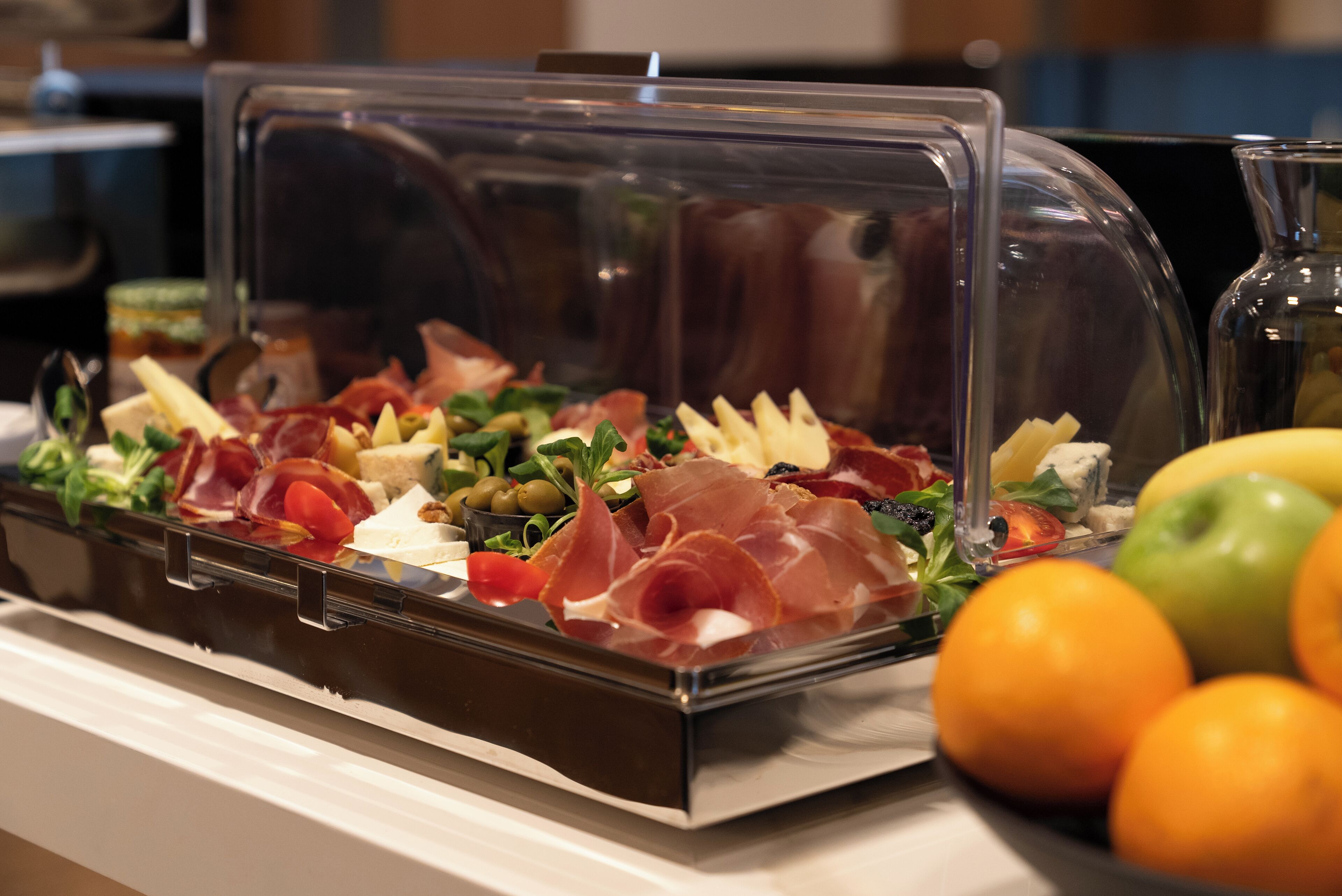 A buffet with a variety of food items including meats, cheeses, and fruits.