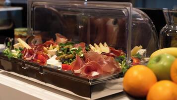 A buffet with a variety of food items including meats, cheeses, and fruits.
