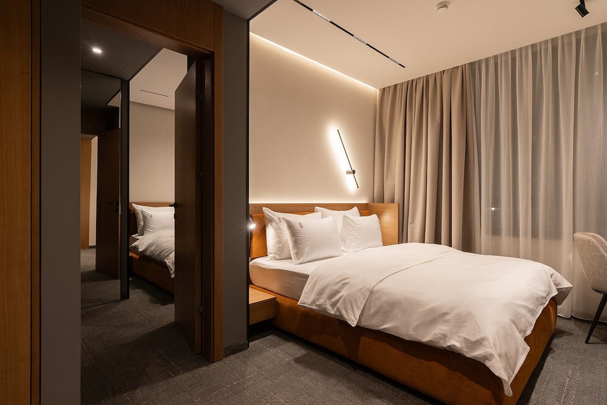 Une chambre d’hôtel moderne avec un grand lit, une table de chevet, une chaise et un miroir.