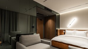A modern hotel room with a bed, a sofa, a desk, and a mirror. - Garni Hotel Galeria  (Banja Luka)