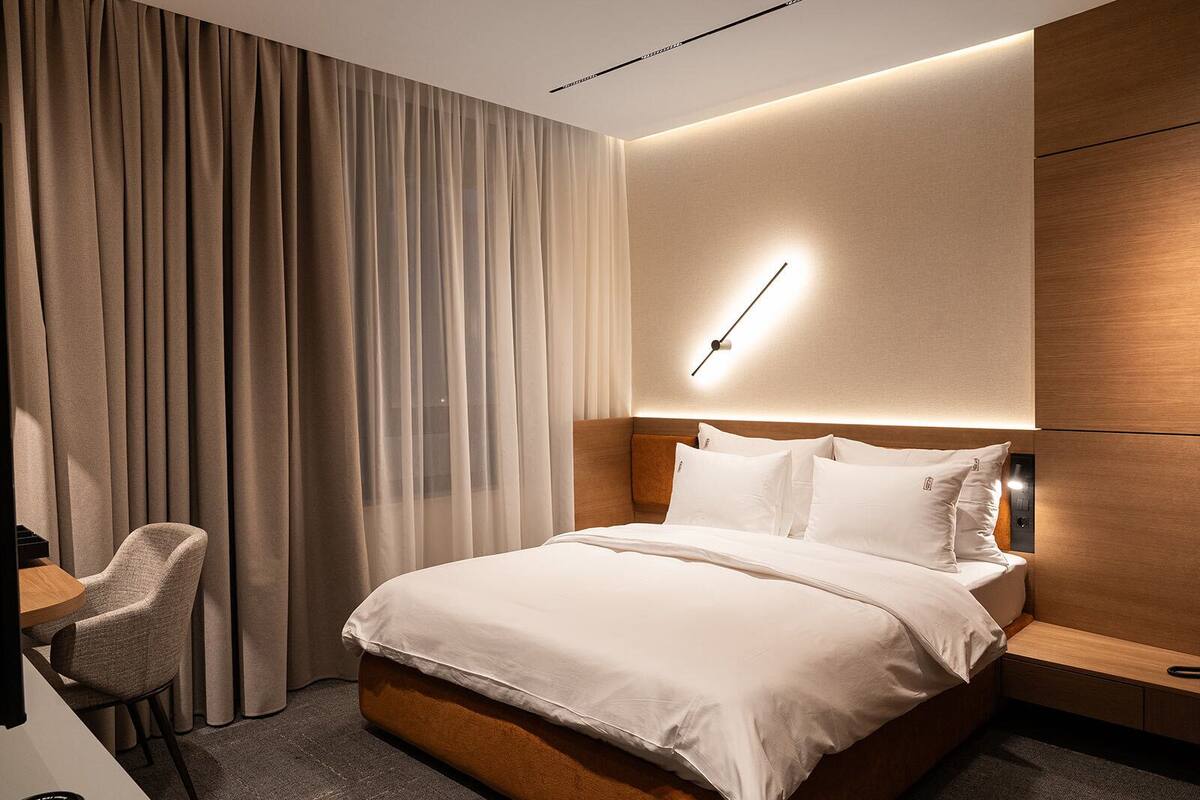 Une chambre d’hôtel moderne, dotée d’un grand lit, d’un bureau et d’une chaise.