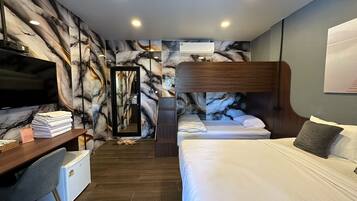 A hotel room with a bed, a desk with a TV, a mirror, and a marble-patterned wall.