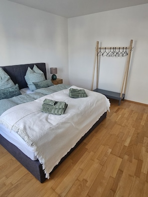 A bedroom with a bed, pillows, a bedside table, a lamp, and a wooden floor. - Premium apartment on Mühlbach in the center (Bad Aibling)