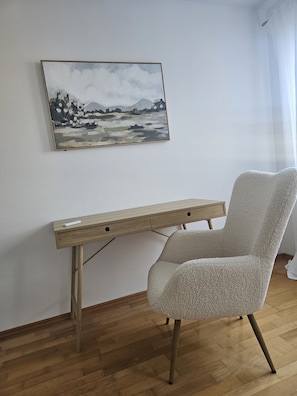 A room with a wooden desk, a fluffy chair, and a painting on the wall. - Premium apartment on Mühlbach in the center (Bad Aibling)