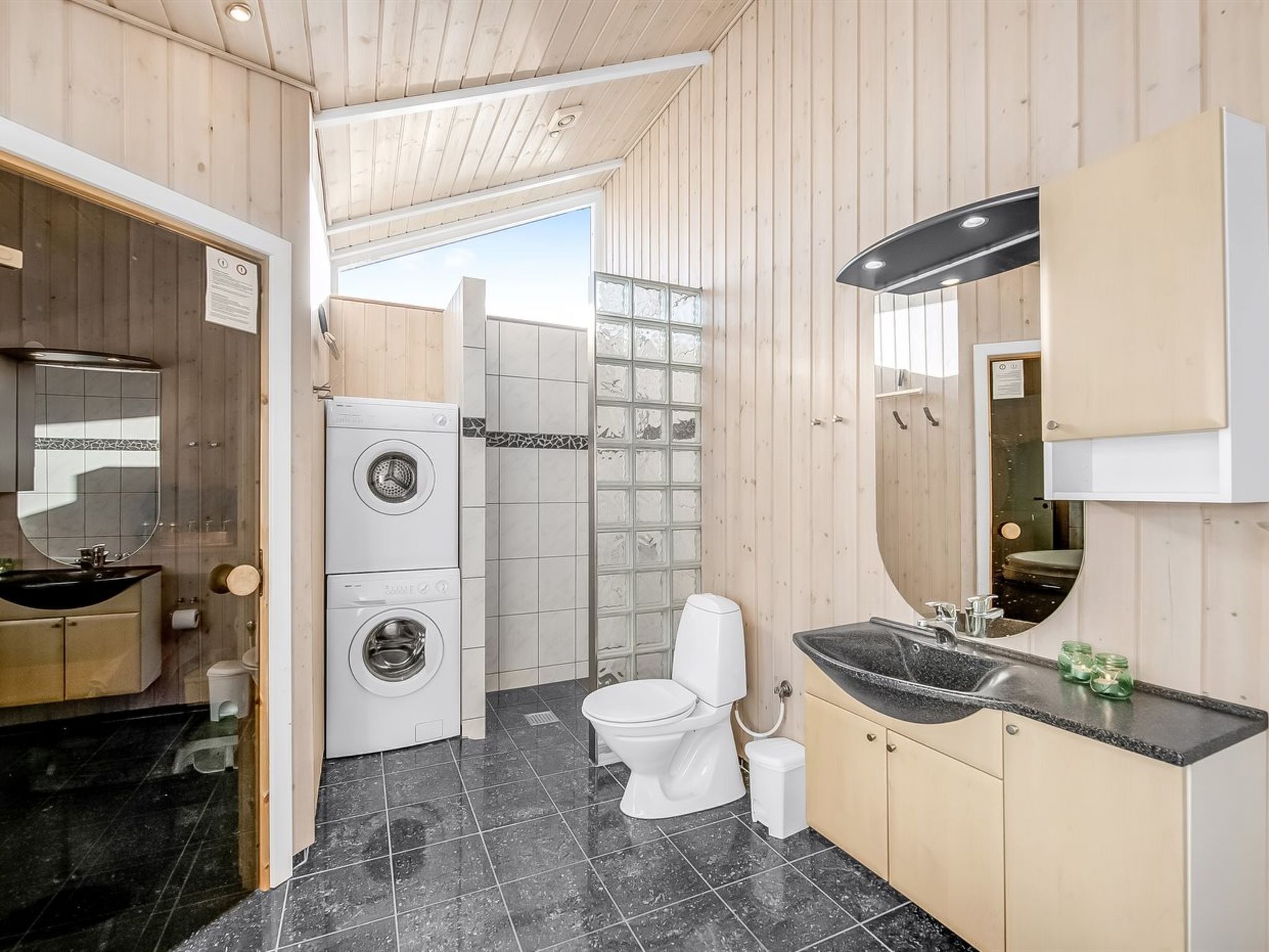 A compact bathroom with a washing machine, toilet, and sink.