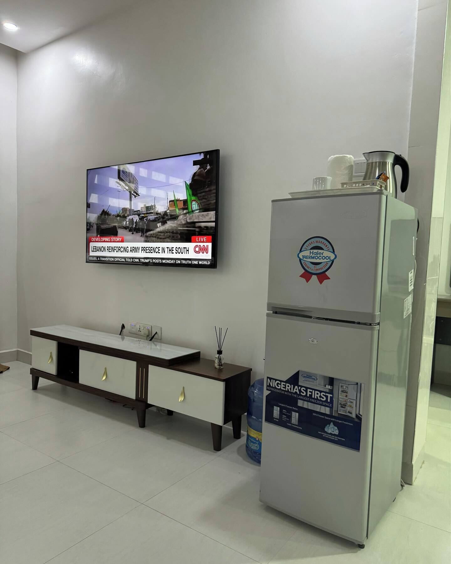 A modern kitchen with a built-in refrigerator, a TV mounted on the wall, and a white countertop.