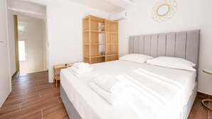 Ein Hotelzimmer mit einem Bett, einem Holzschrank, einem Nachttisch und einer Wand-Klimaanlage.