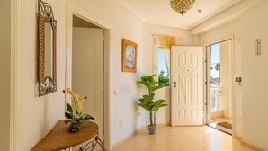 A hallway with a door, a potted plant, a framed picture, and a mirror. - Stunning Villa Rosa Quesada Centre private pool (Ciudad Quesada)