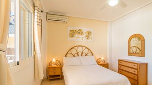 A bedroom with a bed, bedside lamps, a dresser, a mirror, and a wall-mounted air conditioner. - Stunning Villa Rosa Quesada Centre private pool (Ciudad Quesada)