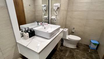 A modern bathroom with a double sink vanity, a toilet, and a hairdryer mounted on the wall.
