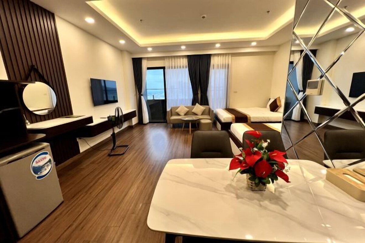 A modern hotel room with a marble table, a sofa, a bed, and a TV.