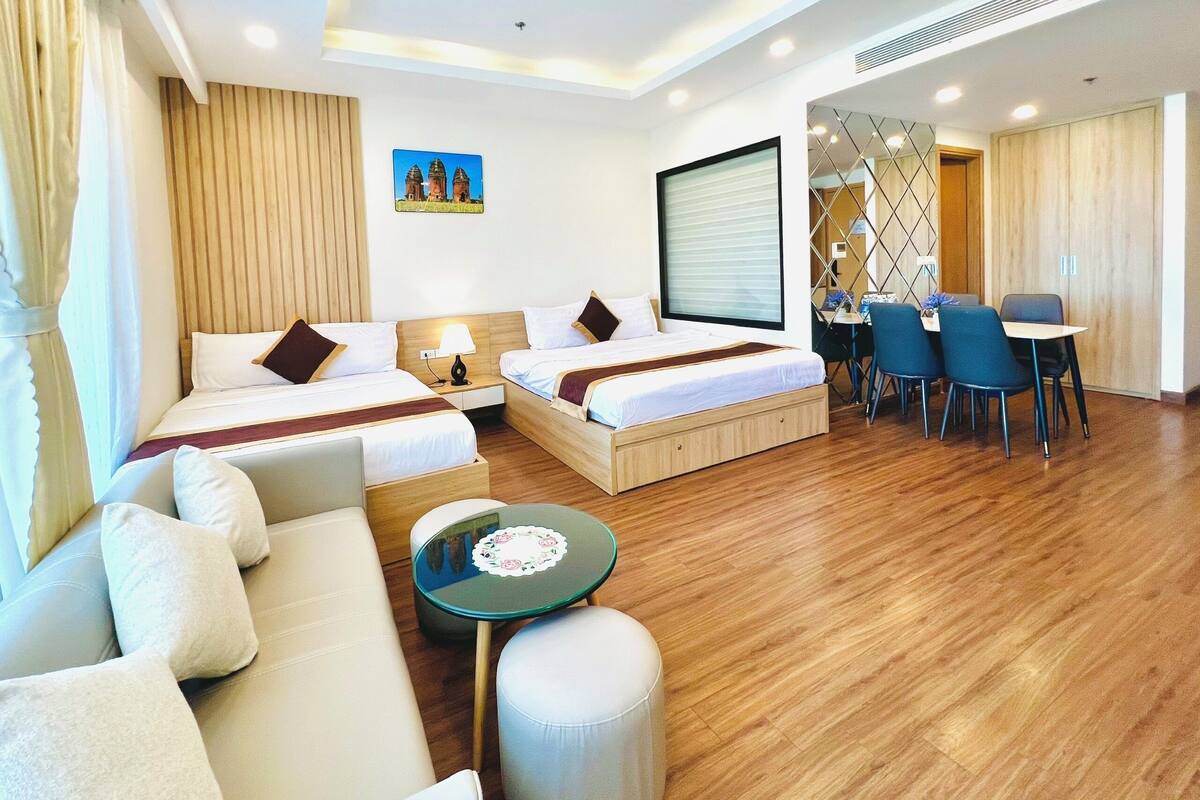 Habitación de hotel con dos camas, un sofá, una pequeña mesa y un comedor con sillas.