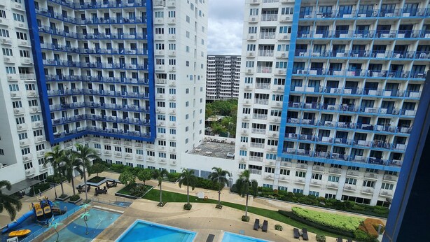 A high-rise residential building with multiple balconies and a rooftop pool area. - MNM Place - Sea Residence - 0A (Pasay)