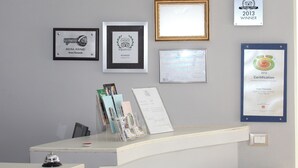 A reception desk with framed awards and certifications, a clear desk organizer, and an exit sign.