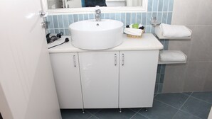 A bathroom with a white sink, a mirror above it, and a tiled floor.