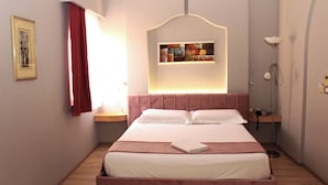 A neatly made bed with a headboard, a bedside table with a lamp, and a wall-mounted artwork above the bed.
