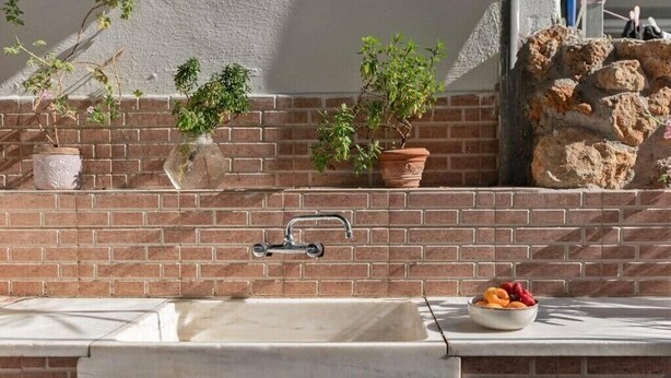 A kitchen with a sink, a brick backsplash, and potted plants. - Casa Valore by 8essentially (Chania)
