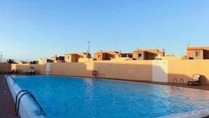 En swimmingpool med liggestole og en klar himmel.