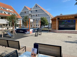 An outdoor area with a playground, a wooden structure, and a building with a sloped roof. - Family-friendly vacation home, attractively furnished, directly on the waterfront (Bruinisse)