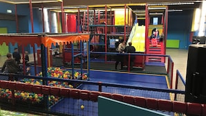 Un'area giochi interna con diverse strutture, una piscina di palline e uno scivolo.