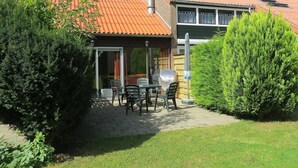 Une maison avec un toit en tuiles, un patio avec une table et des chaises, et un espace extérieur couvert.