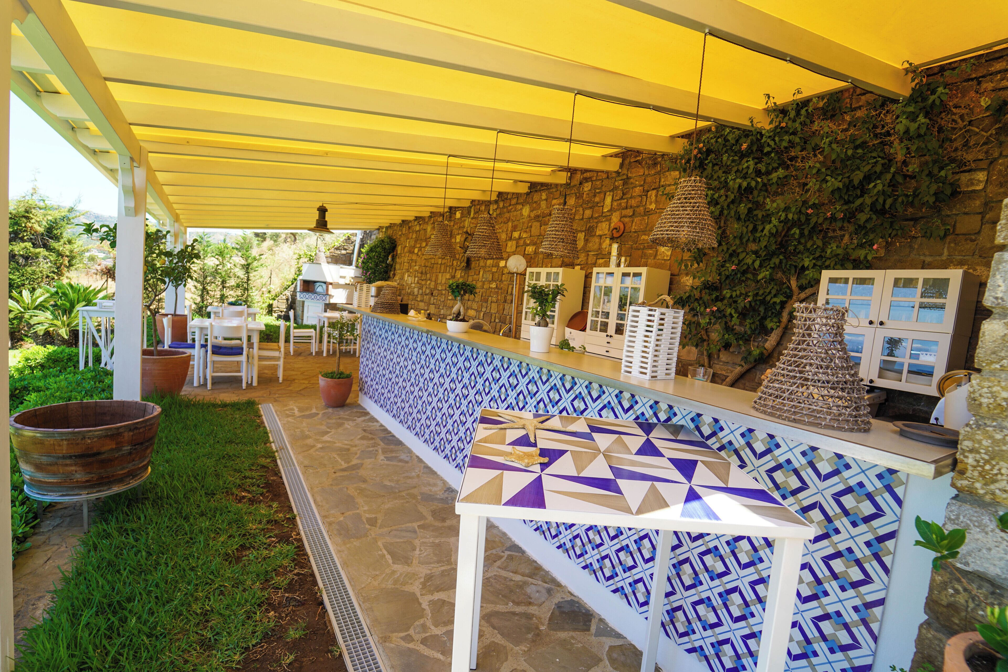 An outdoor patio area with a patterned table, chairs, and potted plants.