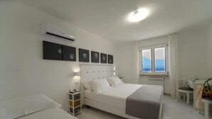 Een slaapkamer met een bed, nachtkastje en een raam met uitzicht.