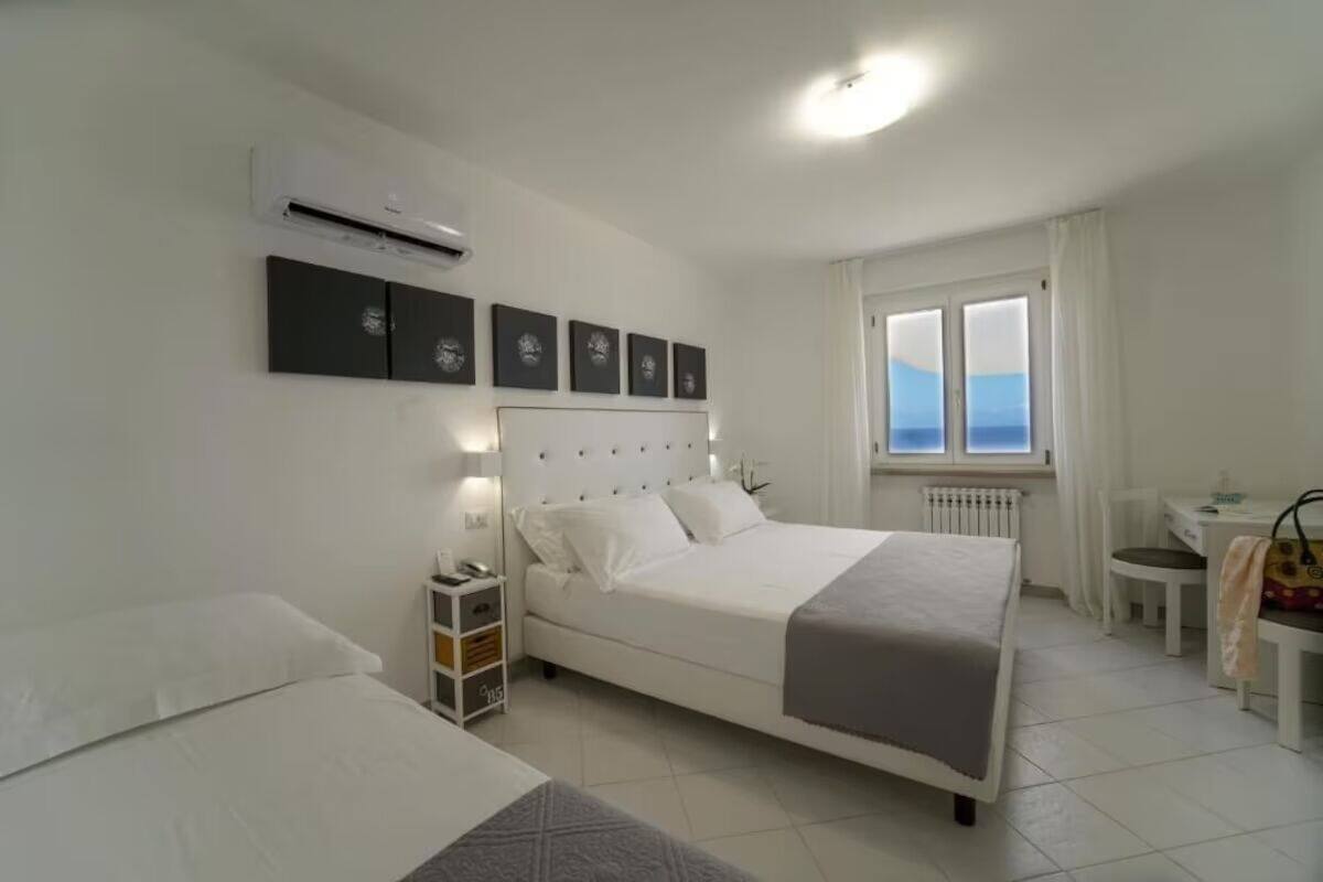 Een slaapkamer met een bed, nachtkastje en een raam met uitzicht.