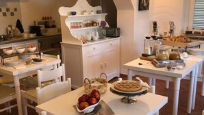 A dining area with white tables and chairs, a buffet setup, and a decorative archway. - Le casette di Ulisse (Castellabate)