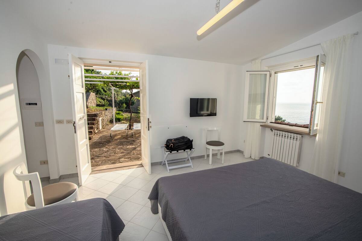 Een hotelkamer met twee bedden, een televisie, een raam met uitzicht en een deur naar een balkon.