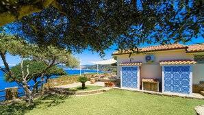 A coastal property with a tiled exterior, a stone wall, and a view of the sea. - Le casette di Ulisse (Castellabate)