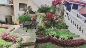 A courtyard with a stone bench, a small table, and potted plants.