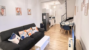 A modern apartment with a black sofa, white coffee table, and a dining area with a table and chairs. - Le Duplex 68m2 apartment close to shops, town center and beach (Calais)