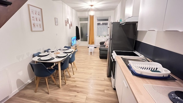 A modern kitchen with a dining area, wooden flooring, and a staircase. - Le Duplex 68m2 apartment close to shops, town center and beach (Calais)