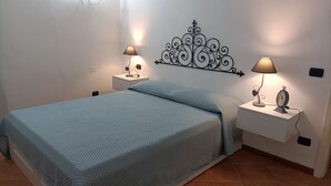 A bedroom with a bed, two bedside tables with lamps, a decorative wall piece, and a clock.