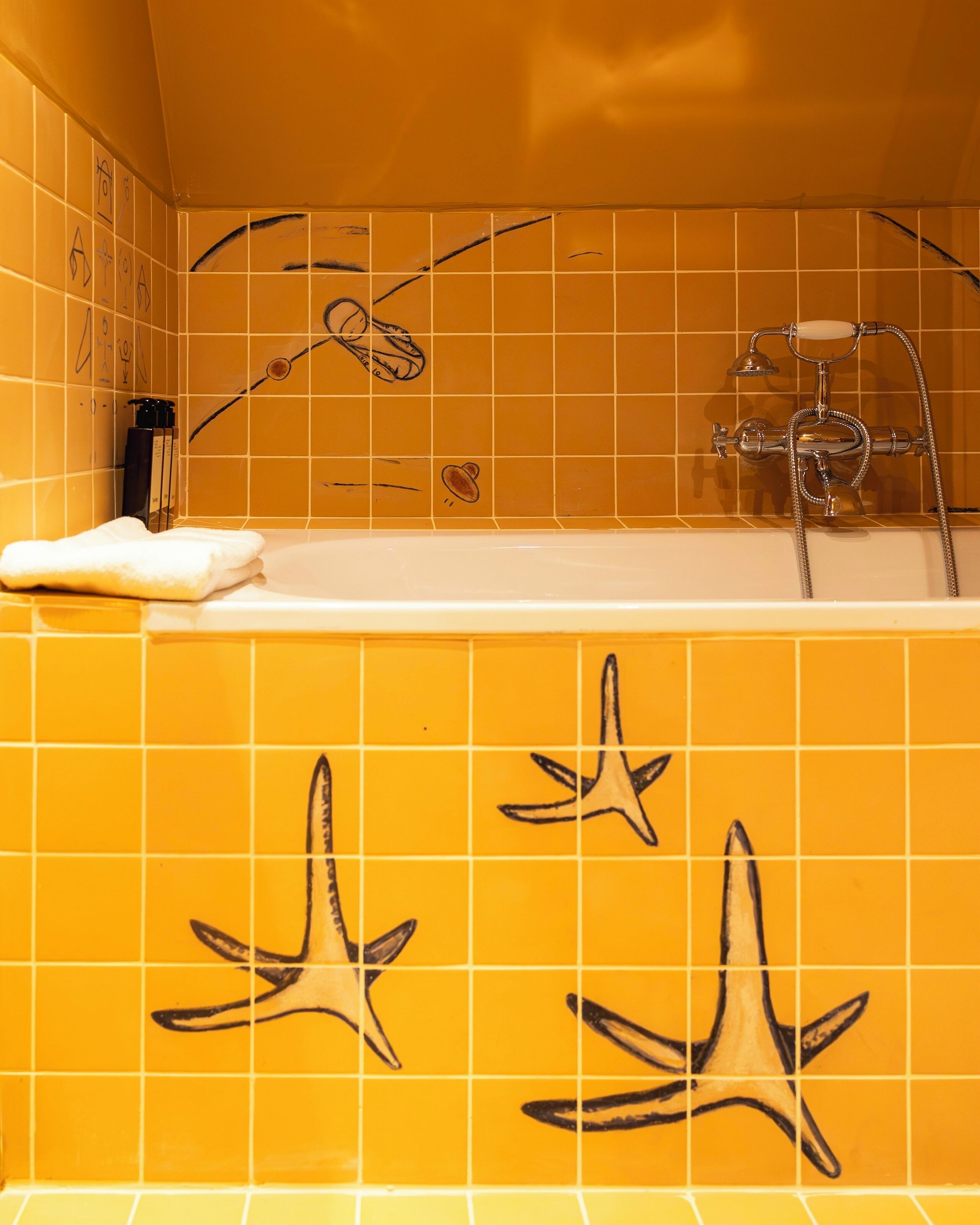 Une salle de bain avec des carreaux jaunes, une baignoire et une douche équipée d’un pommeau de douche amovible.