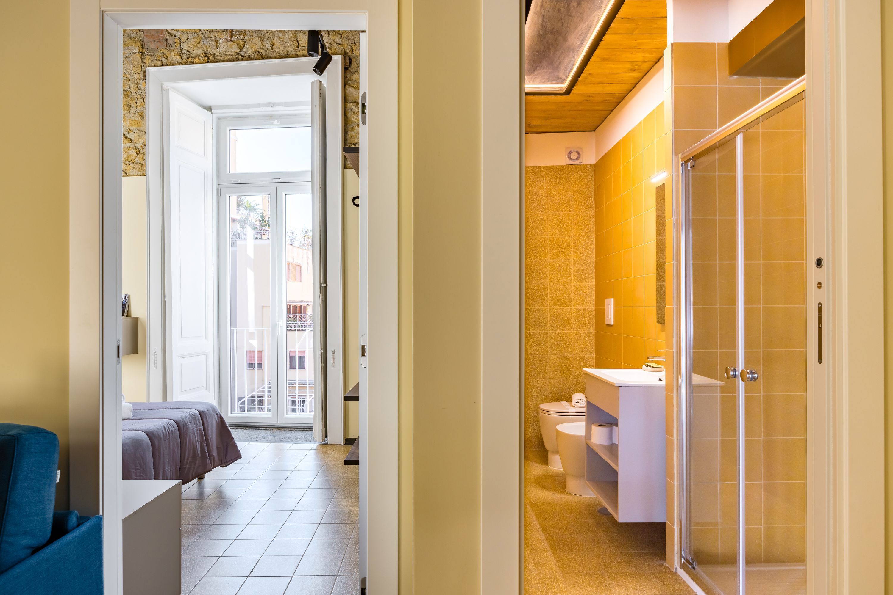 A hotel room with a bed, a bathroom with a shower, and a view of the outside.