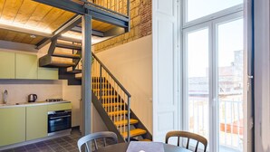 Une cuisine moderne avec un coin repas, un escalier et une grande fenêtre.
