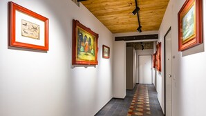 Un couloir doté d’un sol à motifs hexagonaux, de tableaux encadrés accrochés aux murs et d’un plafond en bois.
