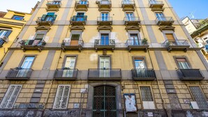 Un immeuble à plusieurs étages doté d’une entrée centrale, de balcons et de fenêtres.
