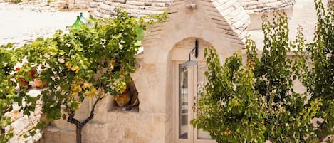 A stone building with a conical roof, a small door, and a white table with chairs.