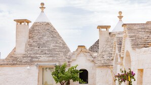 Un edificio de piedra tradicional con techos cónicos, una puerta de madera y un jarrón grande.