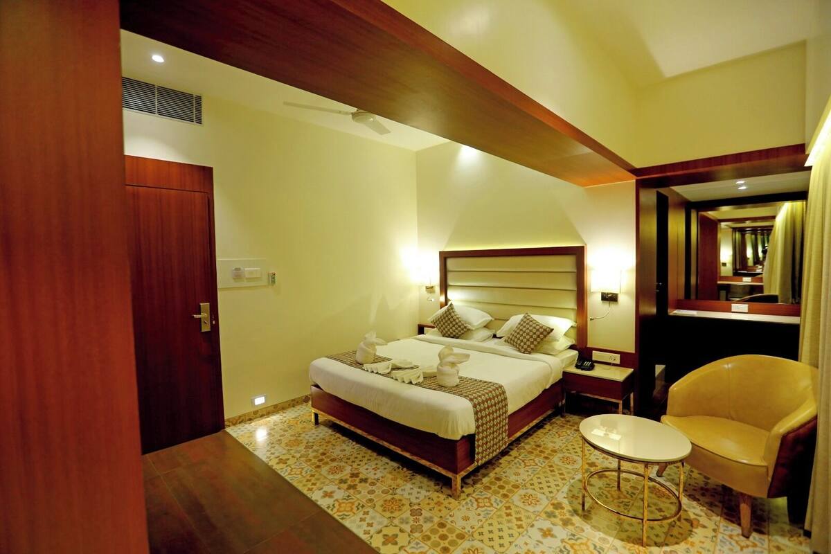 Una habitación de hotel con una cama grande, una mesita de noche, una silla y un espejo.
