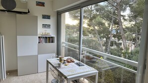 Une petite cuisine avec une fenêtre, un réfrigérateur blanc et une table sur laquelle sont posés quelques objets.