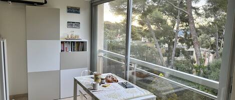 A small kitchen with a window, a white refrigerator, and a table with a few items on it.
