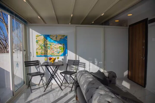 Una habitación moderna con un ventanal grande, un mapa en la pared, un sofá y una mesa con bebidas.