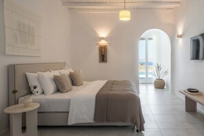 Un dormitorio moderno con cama, mesita de noche, lámpara y vistas al exterior.